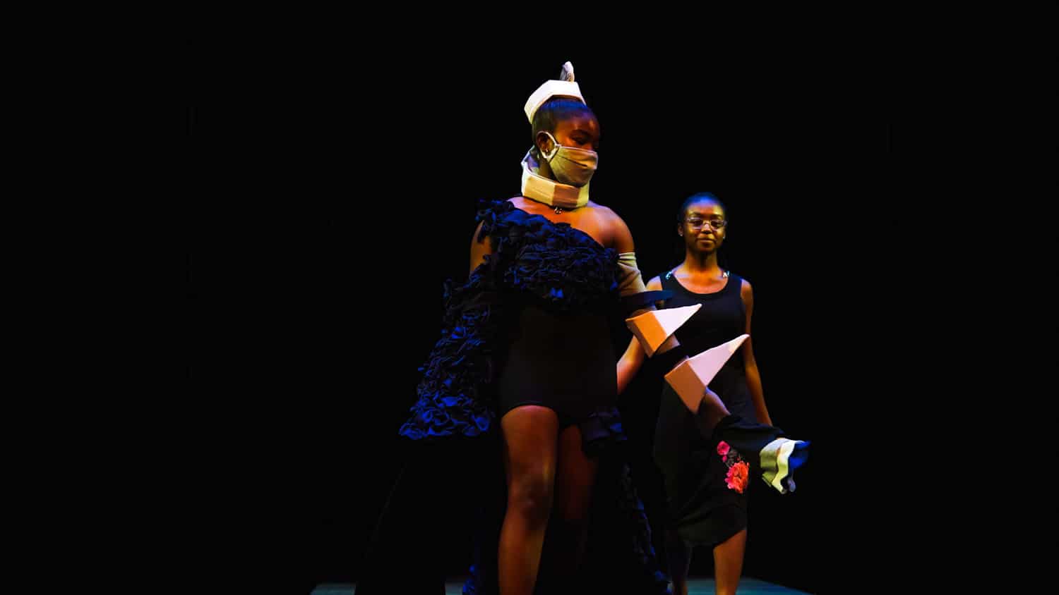 Two students dancing in colorful outfits.